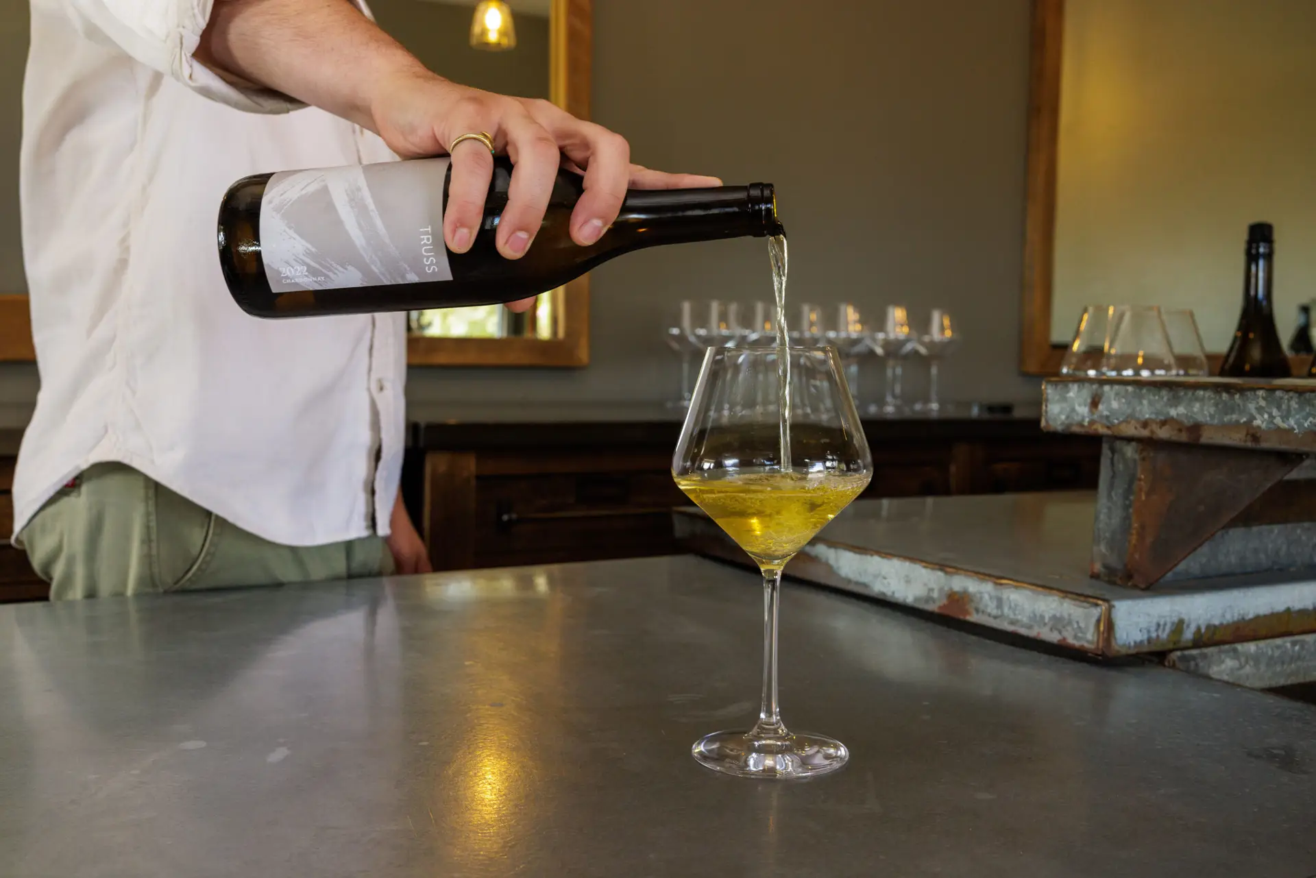Person pouring a glass of 2022 Truss Chardonnay during a wine tasting in Paso Robles, California, inside the Truss Wines tasting room.