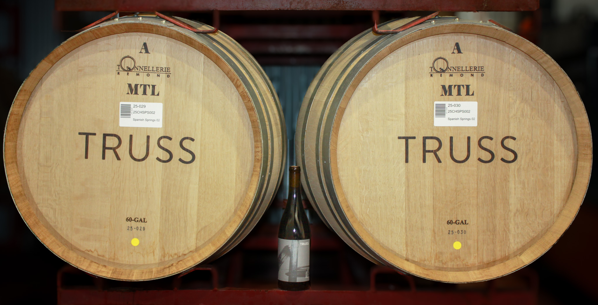 Person walking indoors holding a bottle of dry Provençal-style rosé from Paso Robles, made with Grenache, Syrah, Mourvèdre, and Cinsault grapes, styled with a casual, French-inspired wine aesthetic